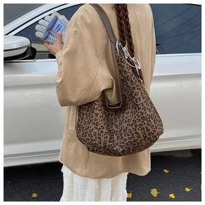 Detail of leopard print tote bag with brown leather strap worn over the shoulder