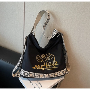Detail of embroidered gold elephant logo on black nylon tote bag with geometric strap