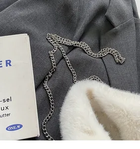 Detail of soft white faux fur texture and elegant silver chain strap on a plush handbag