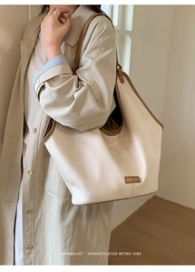 Detailed macro view of cream leather tote texture with dark brown piping and brand tag