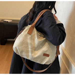 Side view of a large canvas tote bag with brown straps worn on a model's shoulder