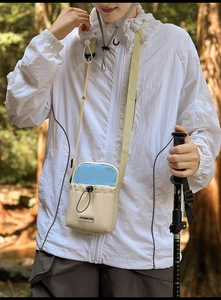 Détail d'un mini sac bandoulière pour téléphone avec cordon et étiquette de marque