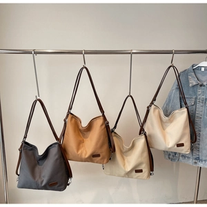Detail of canvas tote bags in grey, khaki, beige, and white colors with leather straps