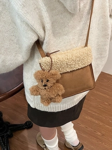 Borsa a secchiello marrone satinata con patta in pile bianco e ciondolo a orso