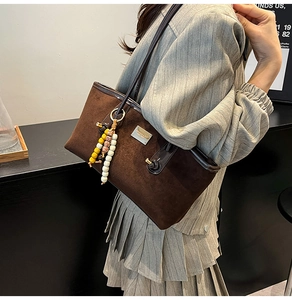 Detail of dark brown faux suede tote bag with colorful bohemian beads and metal plate