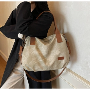 Detail of canvas tote bag with brown leather accents and adjustable shoulder strap