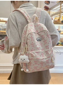 Detail of white corduroy backpack with pink bow patterns and cloud plush charm