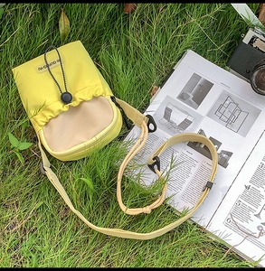 Détail d'un petit sac bandoulière en nylon jaune avec fermeture à cordon