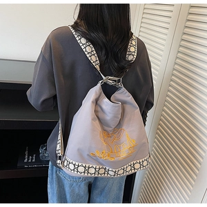 Close-up of elephant embroidery and geometric patterned straps on a grey canvas bucket bag