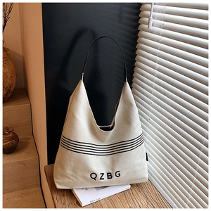 Detail of off-white canvas tote bag featuring black stripes and QZBG lettering design