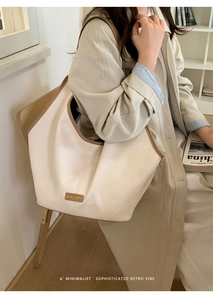 Detailed view of cream leather tote bag with brown contrast stitching and logo