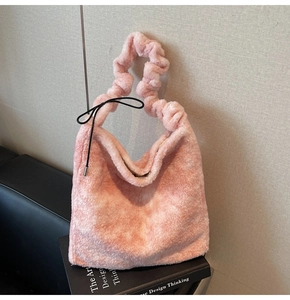 Detailed view of pink plush handbag with ruffled handles and black decorative bow