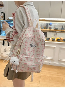 Detail view of cream corduroy backpack with pink bow prints and cloud plush pendant