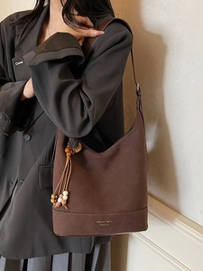 Sac seau en daim marron avec pompon perlé et bandoulière pour un style décontracté