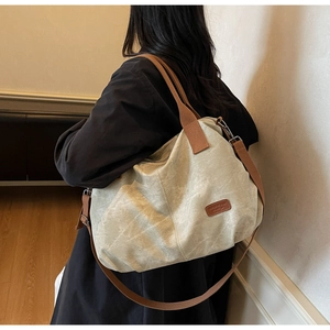 Detail view of large canvas tote bag with adjustable brown strap and leather label