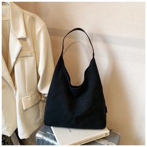 Detail of black canvas tote bag with embossed lettering on a silver suitcase