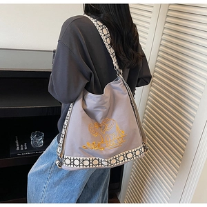 Close-up of gray canvas bucket bag with gold elephant embroidery and jacquard strap