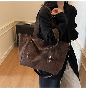 Detail of a deep coffee large tote bag with suede texture and metal ring accents