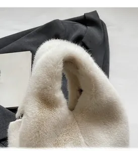 Detail of the soft white faux fur handle on a stylish winter plush bucket bag