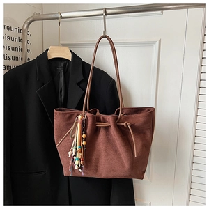 Detail of brown suede tote bag with colorful tassel and vintage beaded charm