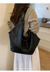 Close-up of a large black matte PU leather tote bag showing texture and brand label