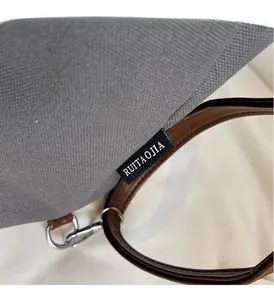 Detail of grey canvas tote with brown leather strap and woven brand tag on the side