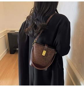 Detail view of leopard print bucket bag featuring premium metal buckle and leather strap