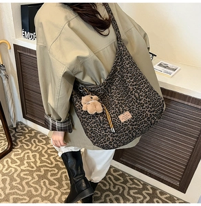 Detail of vintage leopard print tote bag with plush bear charm and striped strap
