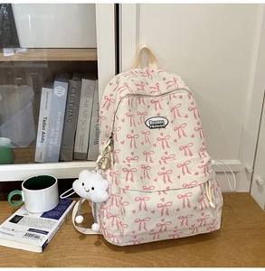 Detailed macro view of corduroy texture and pink bow patterns on the cream school backpack