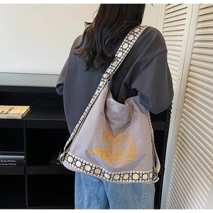 Close-up of grey canvas hobo bag with yellow elephant embroidery and woven strap