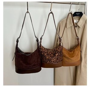 Dettaglio di tre borse hobo in pelle scamosciata caffè, leopardo e caramello con manici