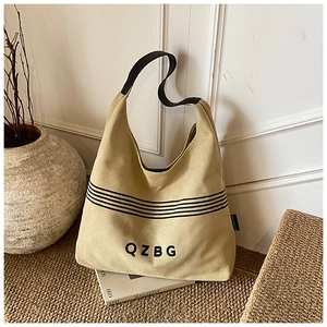 Detail of a large beige canvas tote bag with black QZBG lettering on a textured carpet