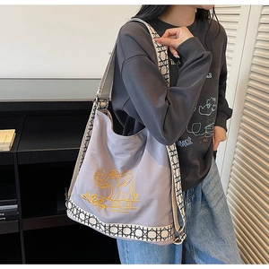 Detail of embroidered gold elephant and MG DF logo on a mauve canvas bucket bag