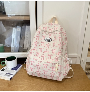Macro view of beige corduroy backpack with pink bow patterns and front zipper pocket