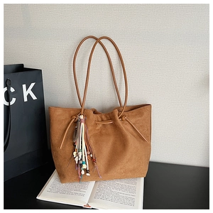 Detail of brown suede tote bag featuring bohemian bead and tassel charms for women