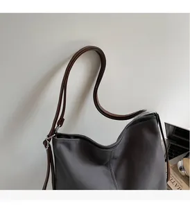 Detail showing grey canvas tote bag with dark brown leather straps and silver metal hardware