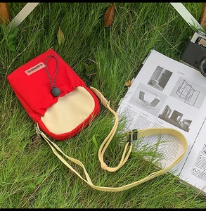 Détail de la sacoche bandoulière rouge et jaune pour gourde avec équipement de plein air