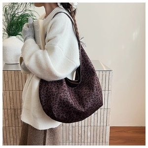 Detail view of large leopard print hobo bag worn by model, showing suede texture and capacity