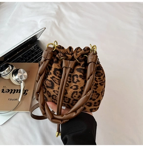 Détail du sac seau à imprimé léopard avec anse tressée sur un lit blanc élégant
