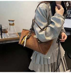 Detail of caramel suede tote bag with leopard charm and stylish brass hardware