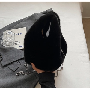 Detail of black faux fur bucket bag with silver metal chain on a stylish set