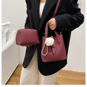 Dettaglio del set borsa a secchiello bordeaux testurizzata con pompon e catena di perle