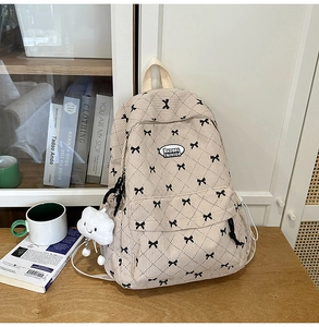 Detail of beige corduroy backpack with bow embroidery and cloud plush charm