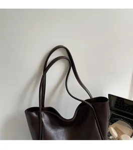 Detail of soft dark brown tote bag with slim shoulder straps and laptop for office use