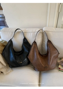 Detail of vintage tote bags in black and brown faux leather on a soft white sofa
