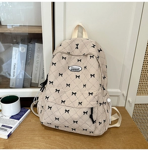 Detail of beige corduroy backpack with quilted pattern and bow embroidery decoration