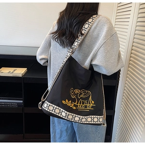 Detail of black canvas bucket bag with gold elephant embroidery and jacquard strap