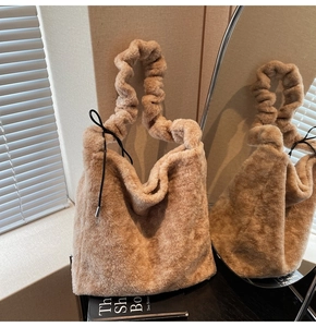 Detailed view of beige plush handbag featuring a scrunchie handle and soft fur texture