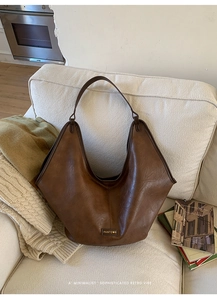 Macro detail of dark brown leather tote bag with PANTO metal logo on a cozy sofa