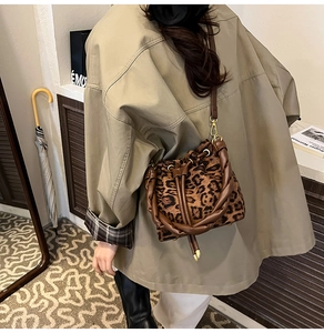Détail du sac seau léopard avec poignée tressée marron dans un cadre de style de vie chic
